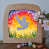 Decorative piece with a colorful tie-dye design and bird silhouette on a wooden frame.
