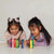 Two young girls playing with colorful crayons on a white surface.