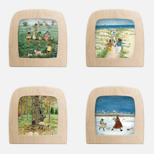 Four square wooden-framed art pieces arranged in a 2x2 grid on a white background. Each piece features a different painted scene: a field scene with children, a beach walk with children, an autumn tree scene, and a snowy winter scene.
