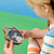 Child holding a cat-shaped wooden object against a colorful background