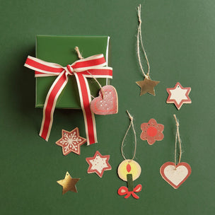 Green gift box with red ribbon and hanging decorative stars and hearts on a green background