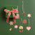 Green gift box with red ribbon and hanging decorative stars and hearts on a green background