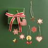 Green gift box with red ribbon and hanging decorative stars and hearts on a green background