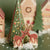 Wooden reindeer figures with a decorated Christmas tree and houses in the background.