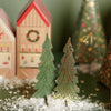 Decorative Christmas scene with trees, houses, and a wreath on a blurred background.