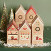 Decorative paper houses with Christmas-themed designs on a green background