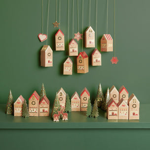 Wooden advent calendar houses with Christmas trees and decorations on a green background