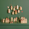 Wooden advent calendar houses with Christmas trees and decorations on a green background