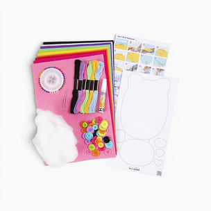 Crafting kit with pink mat, colorful buttons, templates, and other supplies on a white background