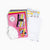 Crafting kit with pink mat, colorful buttons, templates, and other supplies on a white background