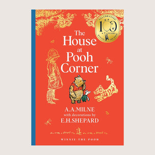 Book cover of 'The House at Pooh Corner' with illustrations of a child, Pooh bear, and Tiger on a red background.