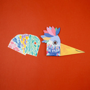 Colorful bird-shaped product with 'Be Wild!' text on an orange background