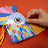 Colorful paper craft with a hand interacting with it on an orange background
