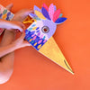Child's hands holding a colorful paper turkey craft against an orange background