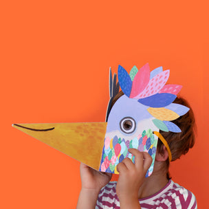 Child wearing a colorful paper mask against an orange background