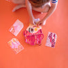 Child playing with colorful paper cutouts on an orange surface