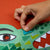 Hand interacting with a colorful children's book on a red background
