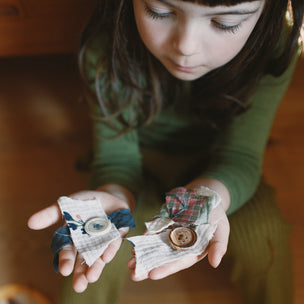 Grapat Avent Calendar 2025 Child holding two small paper crafts on a wooden floor