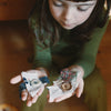 Grapat Avent Calendar 2025 Child holding two small paper crafts on a wooden floor