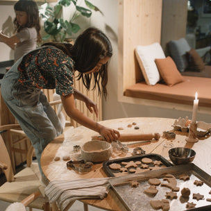 Grapat Avent Calendar 2025 Woman baking cookies at a wooden table in a cozy kitchen.