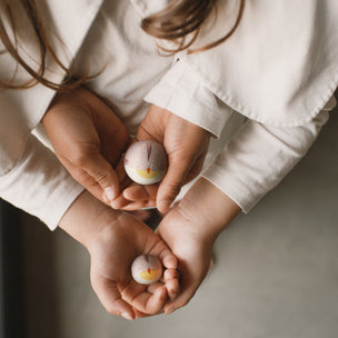 Two children holding small decorative eggs against a neutral background