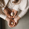 Two children holding small decorative eggs against a neutral background
