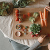 Grapat Advent 2025 Person preparing vegetables on a wooden cutting board with carrots, broccoli, and tomatoes.