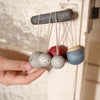 Handmade wooden toy with colorful beads hanging on a string against a neutral background.