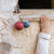 Child's hand reaching towards a red and blue toy hanging from a stone wall.