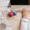 Child's hand reaching towards a red and blue toy hanging from a stone wall.