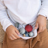 Child holding a small bag filled with colorful eggs on a wooden surface
