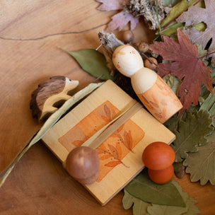 Decorative arrangement with wooden figurines, leaves, and acorns on a wooden surface