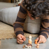 Child playing with wooden figurines on a rug