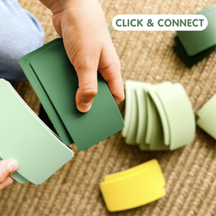 Hands playing with green and yellow blocks on a textured surface