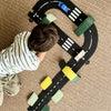 Child playing with a colorful toy road track on a carpeted floor