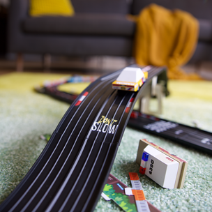 Toy car track set on a carpeted floor with a blurred living room background