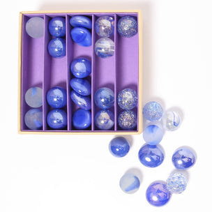 A great selection of various purple glass marbles and pebbles in a purple themed box | © Conscious Craft