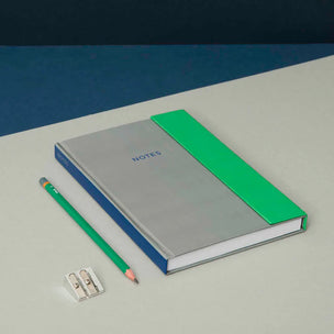Notebook with green accent and pencil on a blue and white background