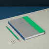 Notebook with green accent and pencil on a blue and white background