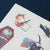 Set of Halloween-themed stickers featuring a ghost, cat, and other elements on a white card with a blue background.