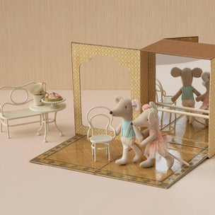 Toy mouse figures in a decorative box with a miniature furniture set on a beige background