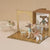 Toy mouse figures in a decorative box with a miniature furniture set on a beige background