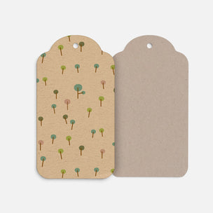Two Maileg paper gift tags with a hole at the top, shown side by side on a light gray background. The left tag has a beige background with a scattered pattern of small stylized trees in green, blue, and pink.