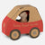 A small Maileg mouse plush toy dressed as Santa Claus sits inside a cardboard car shaped like a delivery vehicle, with the words 'Santa's Parcel Service' printed on the side, photographed on a light gray background.