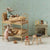 A miniature dollhouse-style room scene with two plush mouse figures arranged on a wooden bunk bed, alongside small furniture pieces, a wallpapered wall, and a fireplace display.