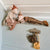 A cozy nursery-style scene with two plush Maileg mice posed on a white paneled ledge. One mouse wears a cream sweater and brown hat, while the other wears striped pajamas.