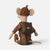 A plush Maileg mouse doll shown from the back, wearing a brown knit hat, brown outfit, and a dark brown backpack with a small gold-tone clasp, photographed on a clean light gray background.