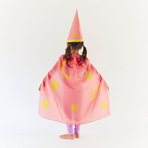 Child wearing a pink wizard costume with yellow stars and a pointed hat on a white background