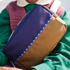 Person holding a purple and brown bag with a blurred background