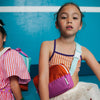 Two children sitting on a blue floor with colorful bags.